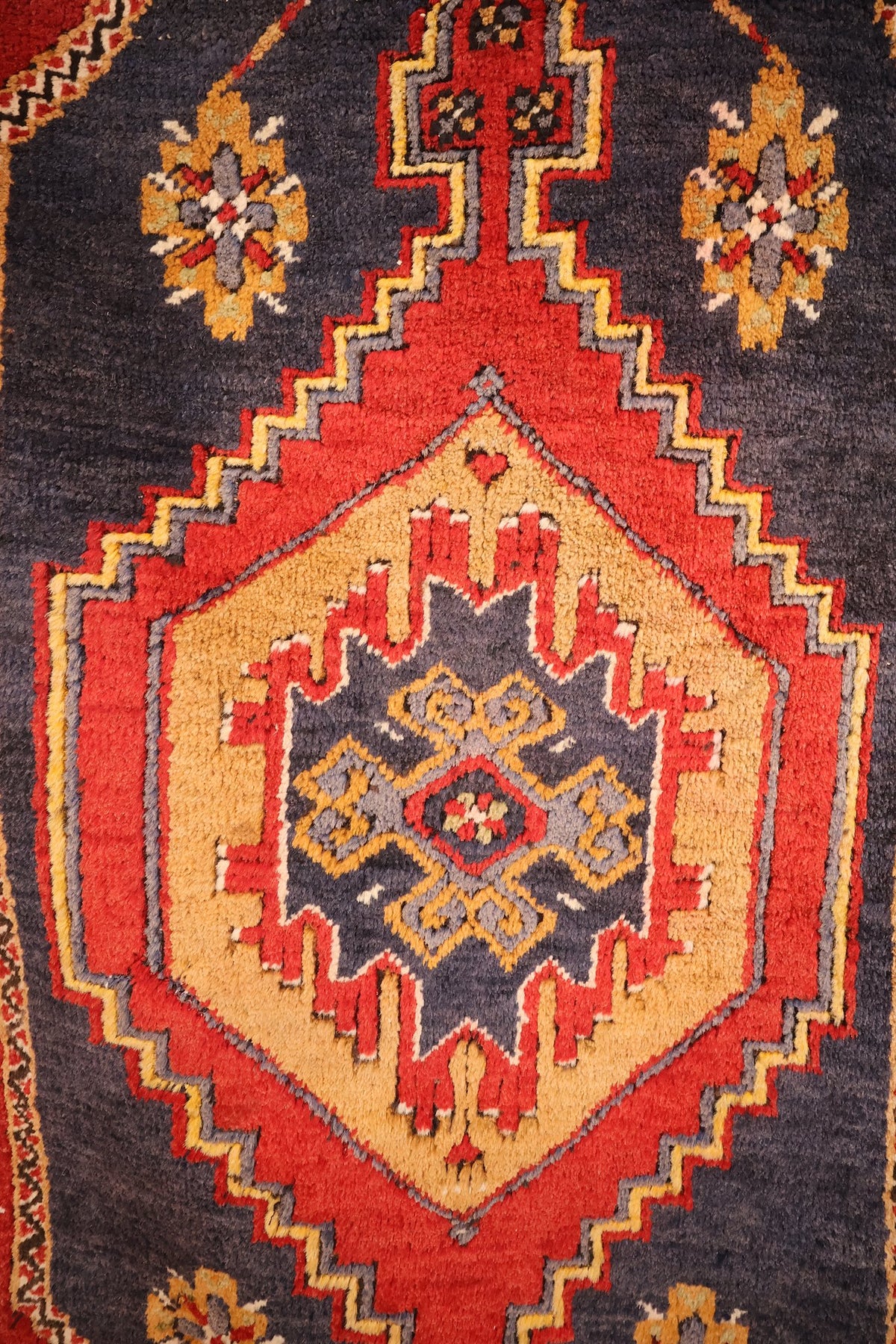 Détail du médaillon crénelé rouge, jaune et bleu-gris du tapis Yahyali