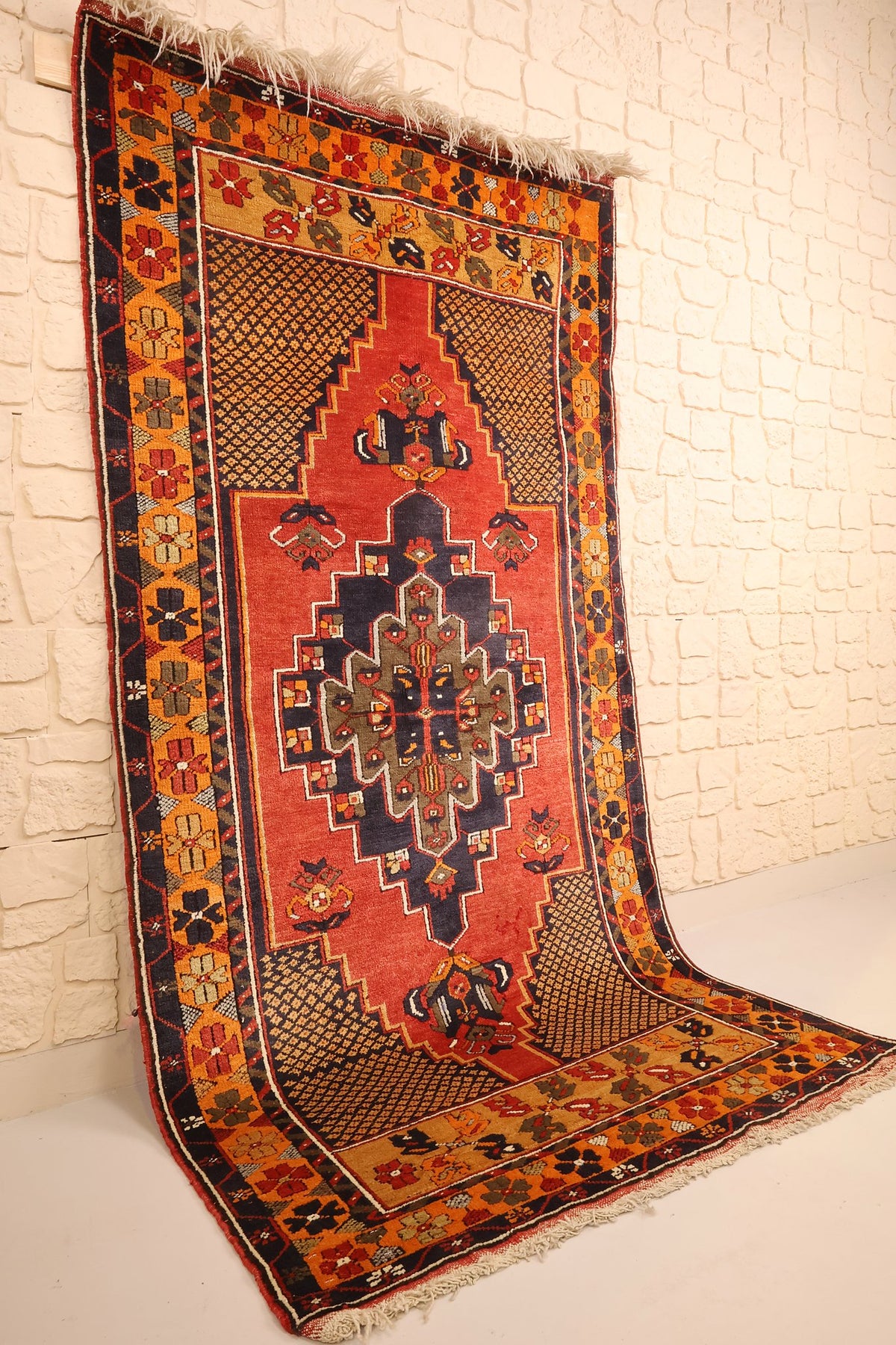 Tapis Yahyali rectangulaire rouge et orange vu de biais, bordure jaune-orangé visible