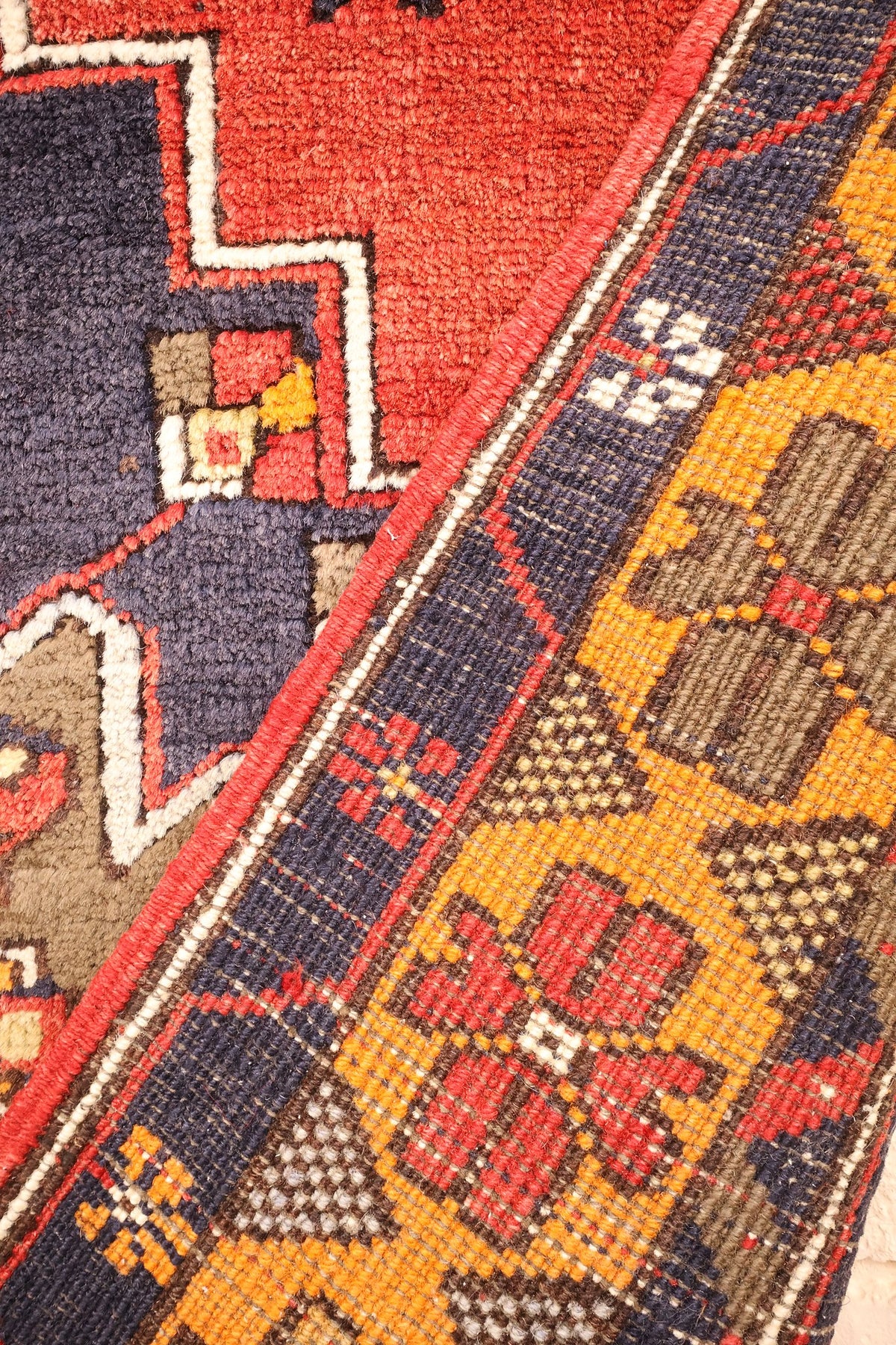 Coin replié du tapis Yahyali rouge, envers et nœuds du décor floral visibles