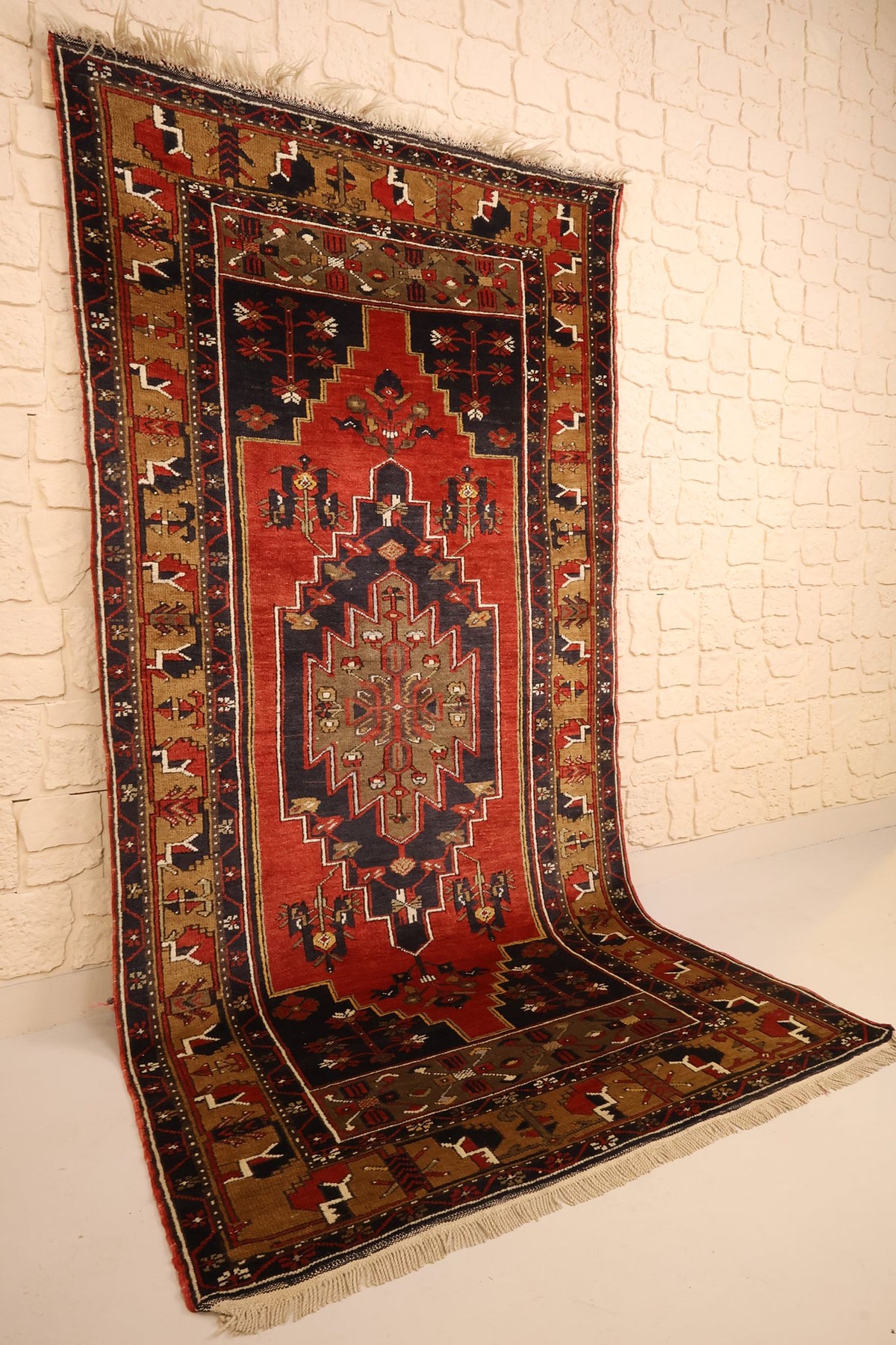Tapis Yahyali rectangulaire rouge et bleu vu de biais, bordures beige doré
