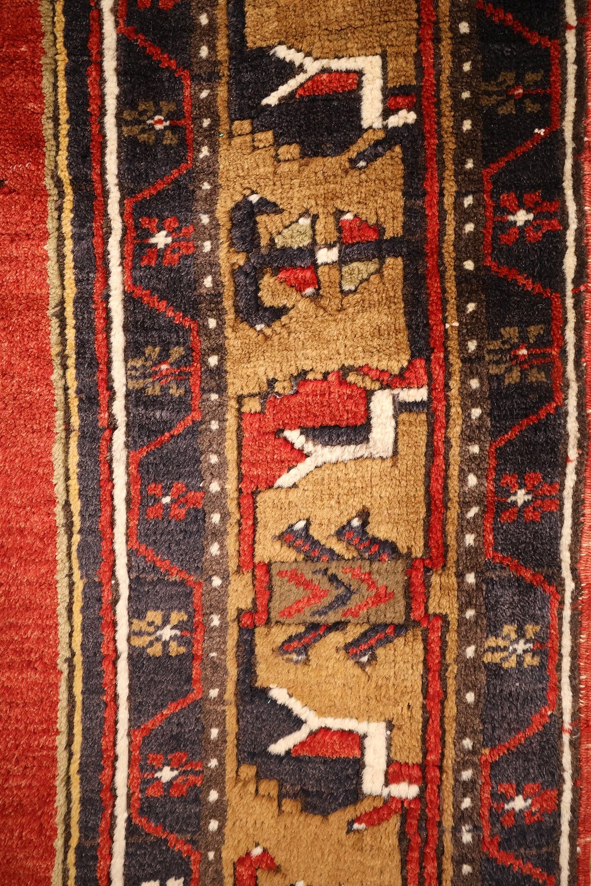 Bordure du tapis Yahyali : galon beige à figures crantées et bandes bleu nuit fleuries