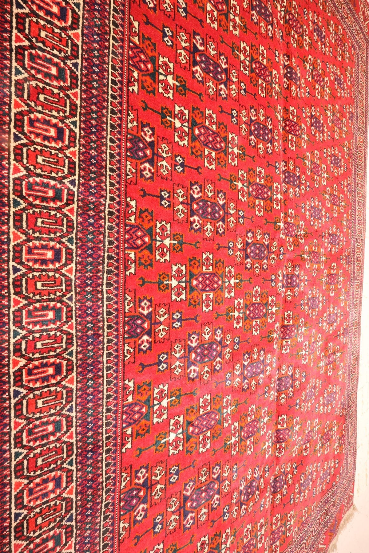 Vue de biais du champ rouge et de la large bande crochetée du tapis Yomut