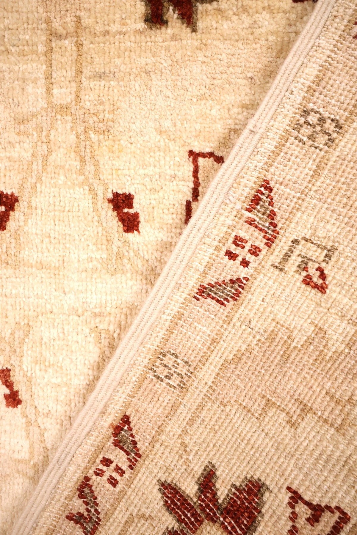 Coin replié du tapis Ziegler en laine nouée main, champ crème et bordure