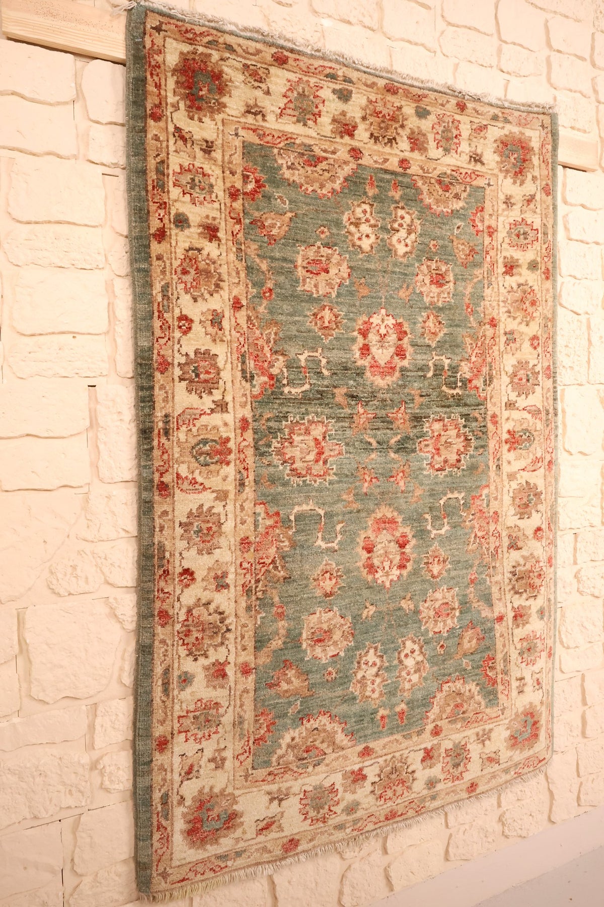 Tapis Ziegler vert et beige en laine, vue de biais sur le champ et les franges claires