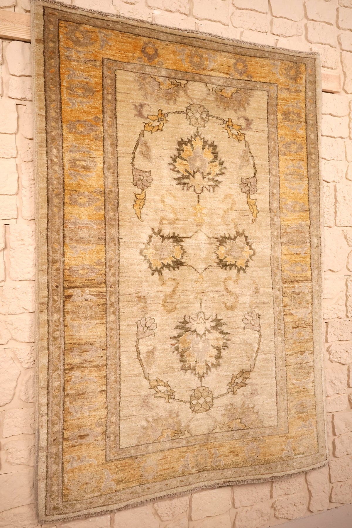 Tapis Ziegler beige et jaune vu de biais, format rectangulaire suspendu au mur