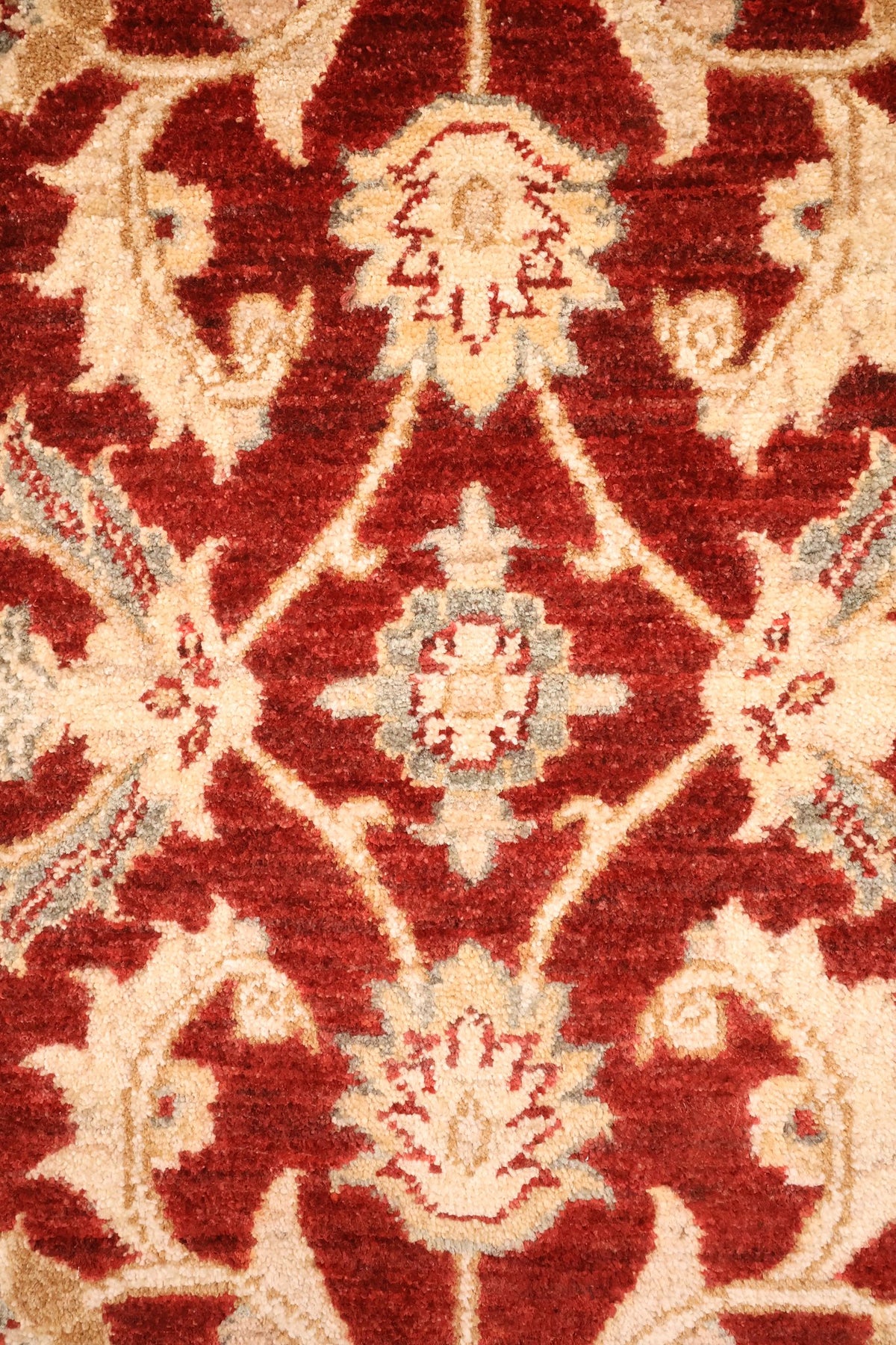 Détail des palmettes et feuilles dentelées beige du tapis Ziegler rouge