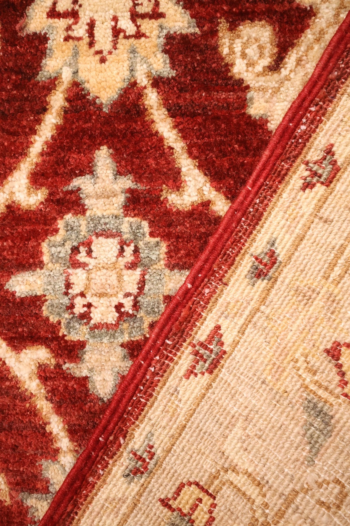 Envers du tapis Ziegler en laine, nœuds visibles le long du coin replié